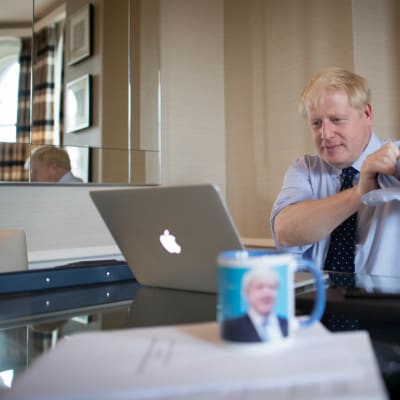 Boris Johnson ses kavla upp ärmarna vid en dator. 