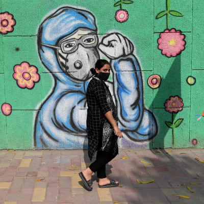 Kvinna promenerar på en gata i New Delhi, Indien