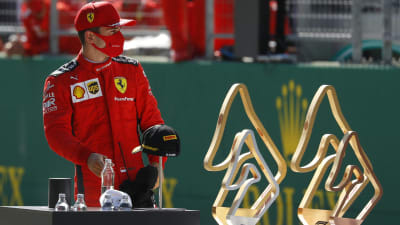 Charles Leclerc står bakom pokalerna.