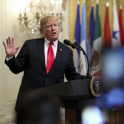 Donald Trump viftar med handen i en talarstol.