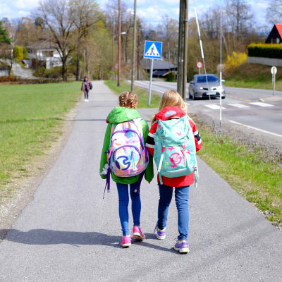 Skolbarn går längs trottoar