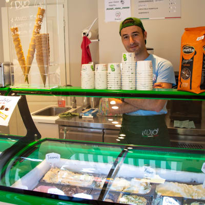 En leende man står bakom en frysdisk med glass i en butik.