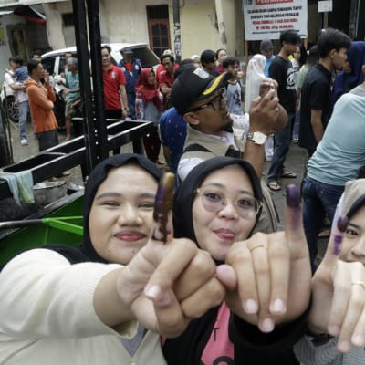 Tre indonesiska kvinnor visar sina bläckmärkta fingrar efter att ha röstat i en vallokal i Jakarta.