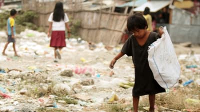 Pojke på Filippinerna plockar material för återvinning i slumområdet utanför Manila.