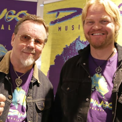 Pertti "Nipa" Neumann ja Otto Kanerva hymyilevät kameralle taustallaan Dingo-musikaali roll-upit.