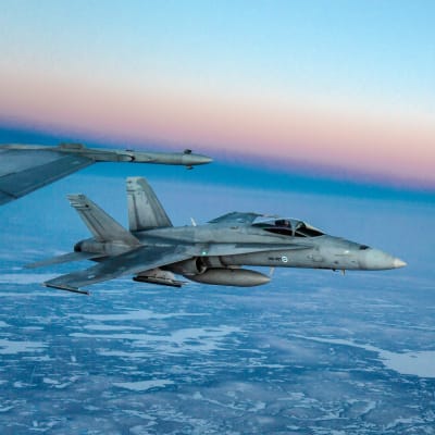 Suomen ilmavoimien Hornet-hävittäjät lennolla korkealla ilmassa talvisaikaan.