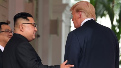 Kim Jong-un håller handen på Donald Trumps arm.