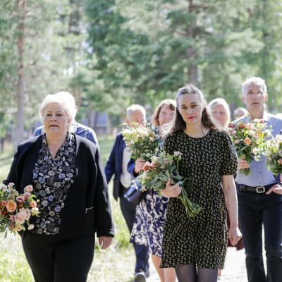 Erna Solberg ja muista muistojuhlaan osallistuneita kukkakimput kädessään.