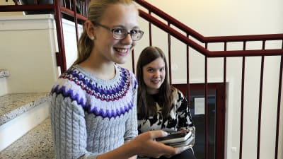 Linnea Vikström och Jennifer Enkvist, elever i Sursik högstadieskola i Pedersöre, sitter i skoltrappan inomhus