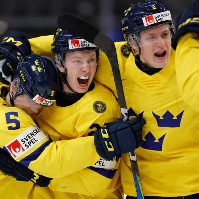 Tre svenska ishockeyspelare i tre kronor-skjortor kramar om varandra på isen.  
