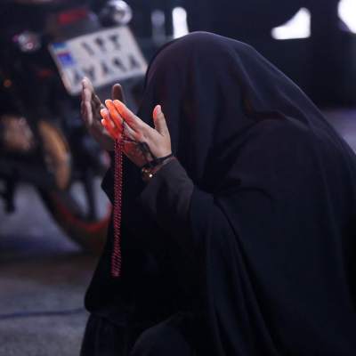 En person med en svart duk över huvueet ber för president Ebraihim Raisi i Teheran.