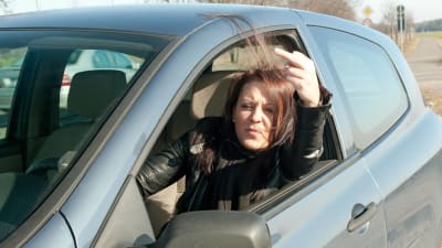Kvinna i bil visar långfingret.