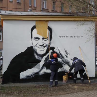 Arbetare målar över en väggmålning av Aleksej Navalnyj.
