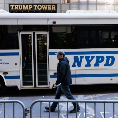 En polis samt polisens buss utanför Trump Tower i New York där Donald Trump väntas tillbringa natten innan han ska ställas inför polis och domstol.