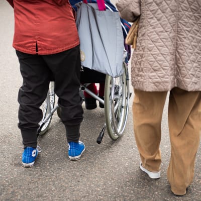 en kvinna skuffar en åldrig i rullstol