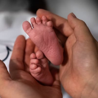 Händer som håller om ett par babyfötter.