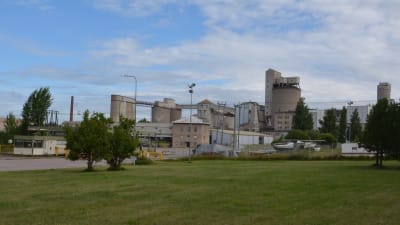 Gamla industribyggnader som använts för att producera kalk, omringade av gröna träd och en gräsmatta.
