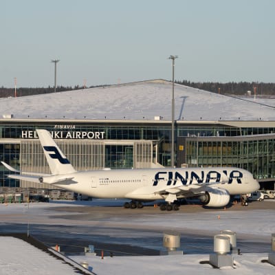 Ett Finnairflyg står parkerat på Helsingfors-Vanda flygplats i vintrigt väder. Solen skiner.