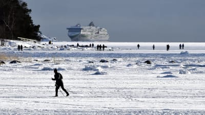 En skidare i soligt vinterväder på isen utanför Helsingfors.