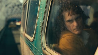 Arthur (Joaquin Phoenix) sitter i en buss och tittar ut genom fönstret.