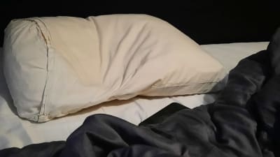 En dyna och ett täcke i en tom säng