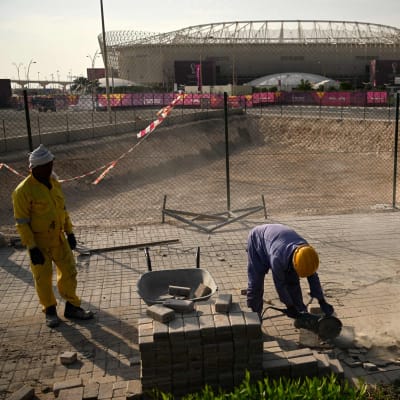 Työntekijöitä rakentamassa tietä jalkapallostadionin ulkopuolella.