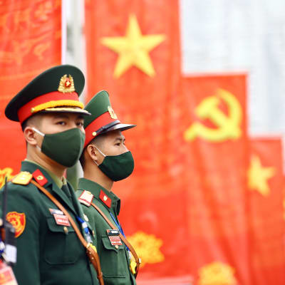 Soldater i förgrunden. I bakgrunden Vietnams och kommunistpartiets flaggor.