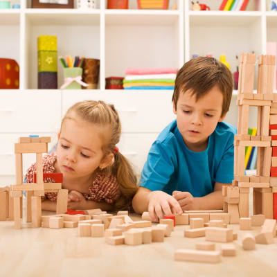 två barn leker med byggklossar på golvet