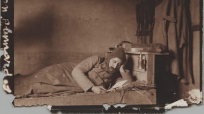 En soldat ligger och läser på sin fältbädd under första världskriget.