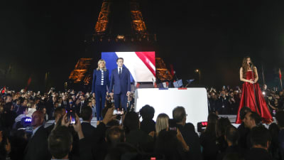 Emmanuel Macron och hans fru Brigitte Macron framför sina anhängare med Eiffeltornet i bakgrunden.