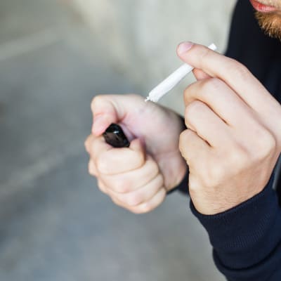 Närbild på en anonym man som håller på att tända en joint.