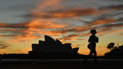 En kvinna springer utanför operahuset i Sydney. 