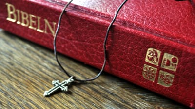 Ett band med ett litet kors är placerat på Bibeln.