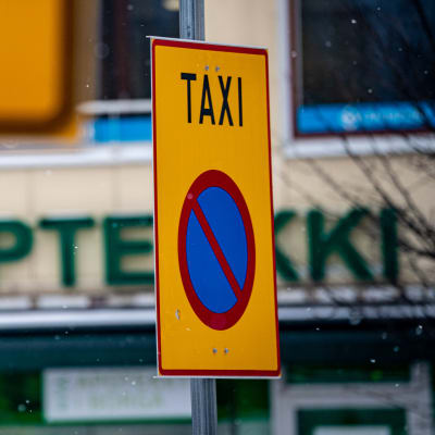 Taxi-kylttejä talvisessa kaupunkimaisemassa.