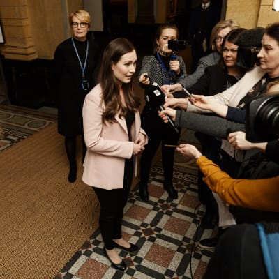 Sanna Marin står i Ständerhusets aula omringad av journalister.