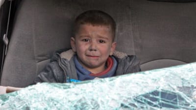 en gråtande pojke sitter i en bil efter en flygräd i staden Ariha i Idlib i Syrien.