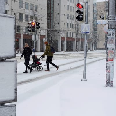  Jalankulkijoita lumisateisessa Ruoholahdessa Helsingissä lauantaiaamuna.