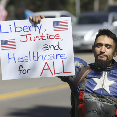 En demonstrant håller upp ett plakat med krav på vård för alla amerikaner.