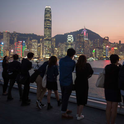 Turister tittar på solen som går ner bakom Hong Kong vid Victoria Harbour. 