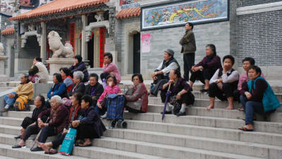 Kinesiska åldringar pausar på en trappa framför ett tempel i Hongkong. 