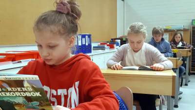 Skolelever läser i ett klassrum. 