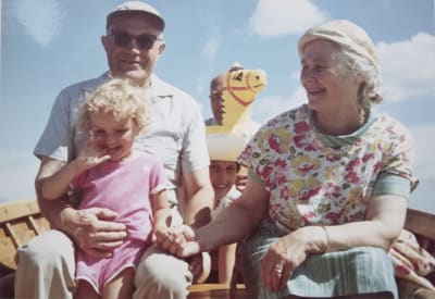 glatt färgfoto från 60-talet, ett litet barn med två äldre personer i en båt