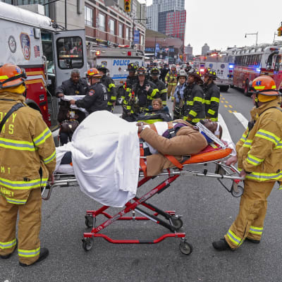 Räddningspersonal och -fordon utanför stationen Atlantic Terminal i New York efter en tågolycka där över 100 människor kommit till skada. I mitten av bilden ligger en man på bår.