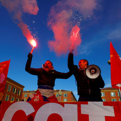 kaksi mielenosoittajaa soihtujen ja lippujen kanssa Nizzassa