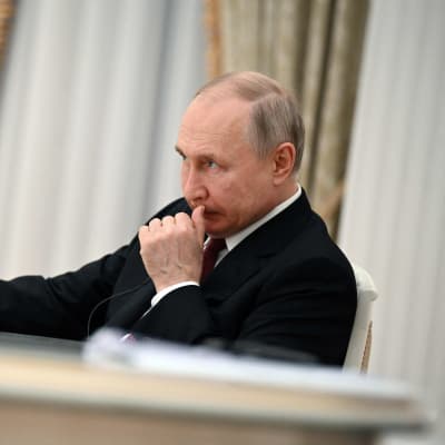 Vladimir Putin sitter vid ett bord.