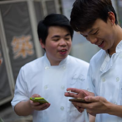 Två män i Hong Kong står och spelar på sina telefoner under en arbetspaus.