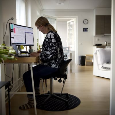 Kvinna jobbar vid dator i sitt hem