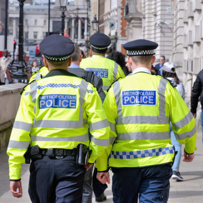 Två poliser går i London. Deras ryggar är mot kameran.