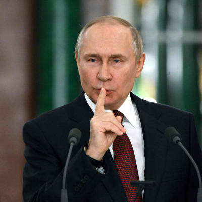 Rysslands president Vladimir Putin håller ett finger framför munnen.