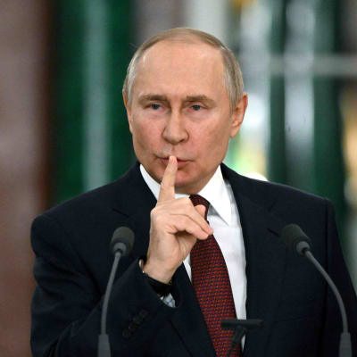 Rysslands president Vladimir Putin håller ett finger framför munnen.